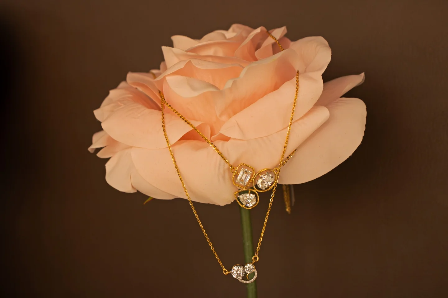 Aurique gold pendants with lab-grown diamonds draped over a pale rose